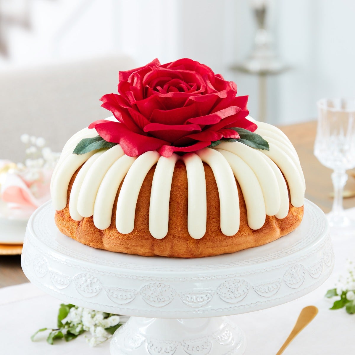 10 in bundt cake with signature frosting and topped with red rose flower.