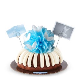 A bundt cake topped with a blue bow and adorned with soft white wings. 