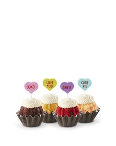 Mini Bundt cakes with white frosting, topped with conversation hearts in pink, lime, lavender, and light teal, displaying messages: XOXO, LOVE YOU, SWEET, and CUTIE PIE.