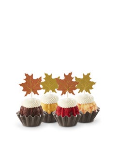 Cupcake-sized mini cakes with frosting and decorated with fall leaves toppers. 