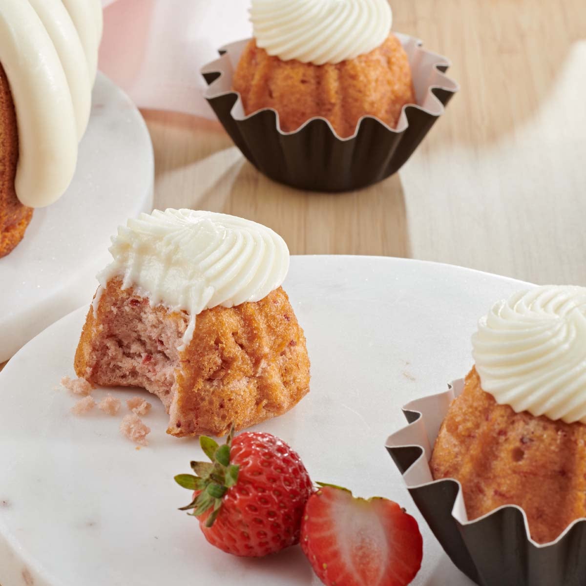 Cupcake sized bundt cakes in Strawberries & Cream flavor with options for decorative toppers. 