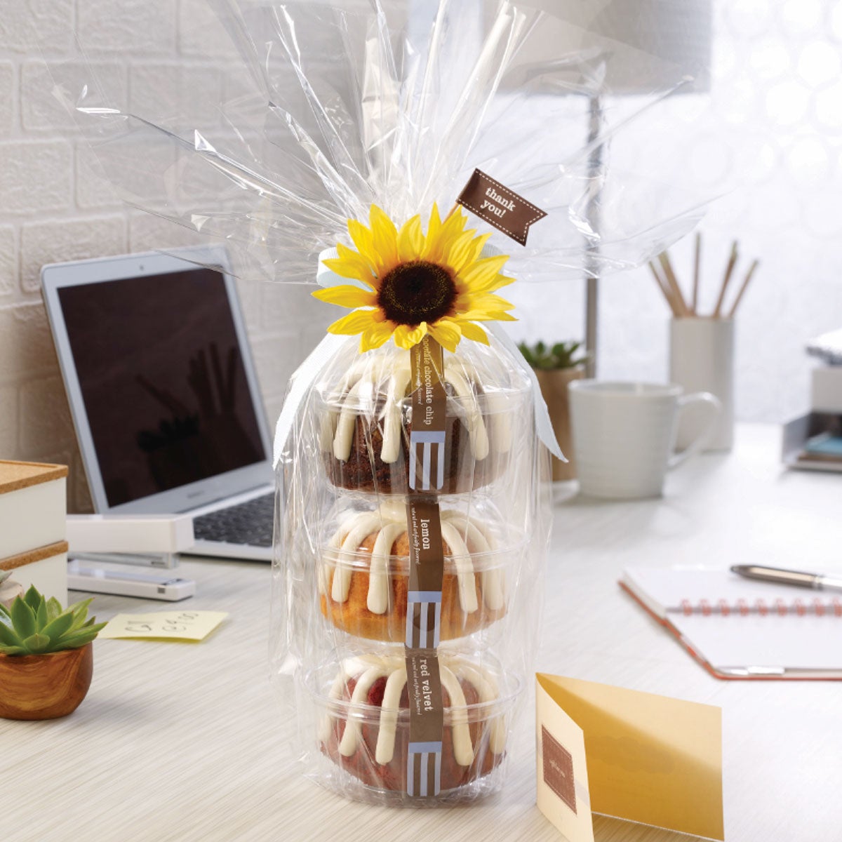 Three personal-size bundt cakes stacked vertically, packaged in a plastic container and gift-wrapped in cellophane. 