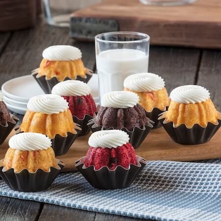 Assortment of Bundtinis on a cake stand with a glass of milk on the table- Shop Bundtinis