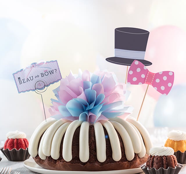 A women pulling bow from Bundt Cake and another women in the back waiting for reveal featuring 