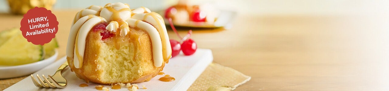 Pineapple Upside Down Bundtlet showing the middle of the cake topped with frosting, drizzle and cherry - Limited Time only