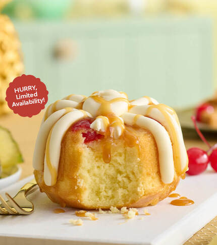 Pineapple Upside Down Bundtlet showing the middle of the cake topped with frosting, drizzle and cherry - Limited Time only